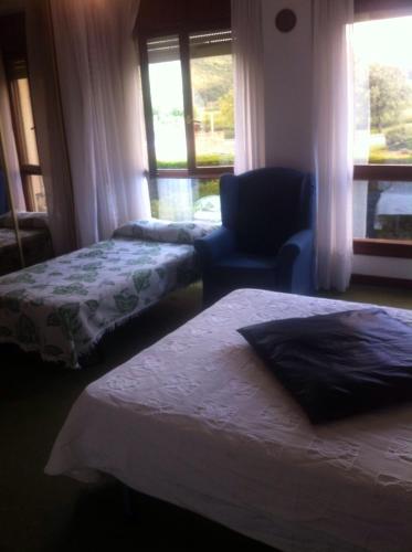 a room with two beds and a chair and a window at Habitaciones López Azcona in Noja