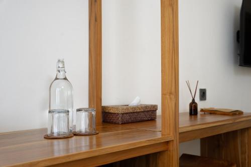 a bottle and two glasses on a wooden shelf at Green Hill Boutique Hotel in Labuan Bajo