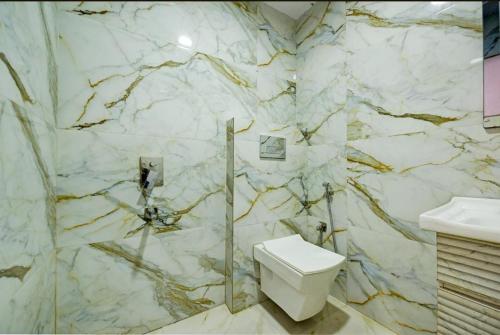 a marble bathroom with a toilet and a sink at Family Stay New Delhi by Sona Hight in New Delhi