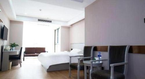 a bedroom with a bed and a table and chairs at GreenTree Inn Fuyang Yijing International North Business in Fuyang