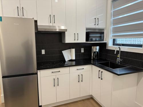 a kitchen with white cabinets and a stainless steel refrigerator at Calm & Cozy Private Suite in Surrey