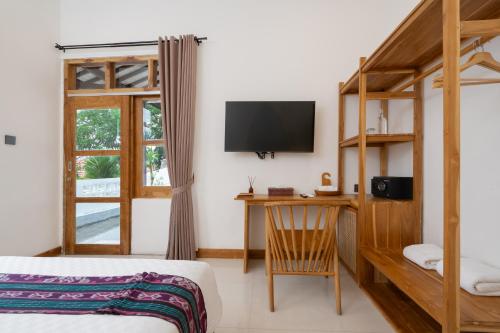 a bedroom with a bed and a desk with a television at Green Hill Boutique Hotel in Labuan Bajo