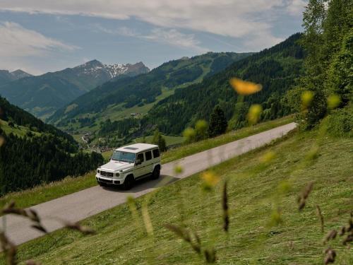 a white van driving down a road in the mountains at DAS EDELWEISS - Salzburg Mountain Resort in Grossarl