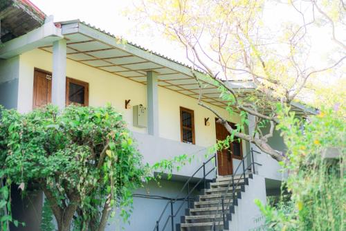 a house with stairs and trees in front of it at Eco Hotel Black & White - Anuradhapura in Mihintale