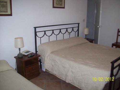 a bedroom with a bed and a nightstand with a bed sidx sidx at Albergo La Perla in Orbetello