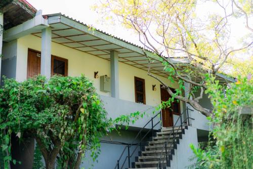 a house with stairs and trees in front of it at Eco Hotel Black & White - Anuradhapura in Mihintale