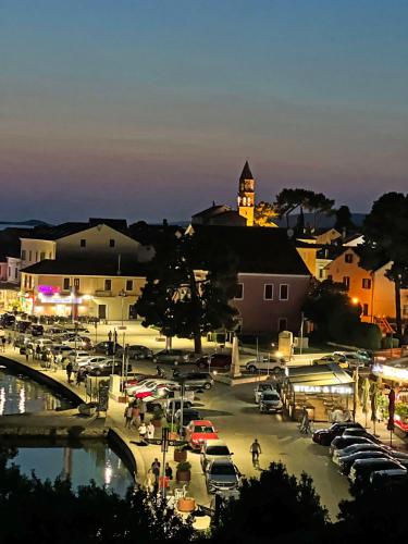 a city with cars parked in a parking lot at night at Ilirija Resort Hotel Kornati in Biograd na Moru