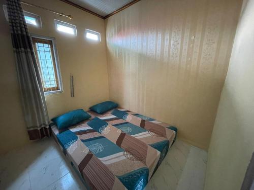 a room with three beds in it with a window at Komodo Homestay in Komodo