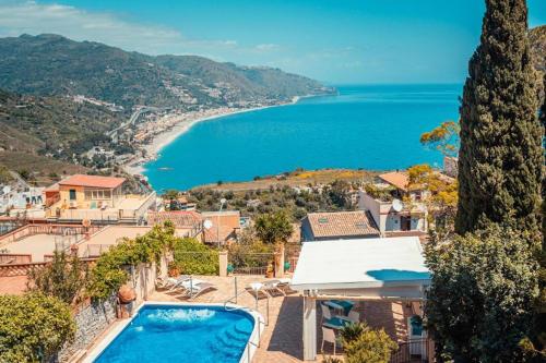 a villa with a swimming pool and a view of the ocean at Sirami Apartments in Taormina