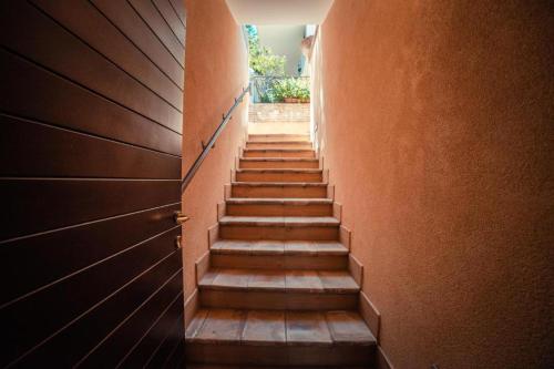 a hallway with wooden stairs in an orange wall at Sirami Apartments in Taormina