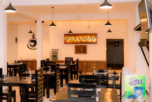 a restaurant with tables and chairs and a sign that reads black and white at Eco Hotel Black & White - Anuradhapura in Mihintale