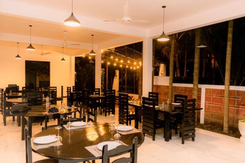 a restaurant with wooden tables and chairs and lights at Eco Hotel Black & White - Anuradhapura in Mihintale