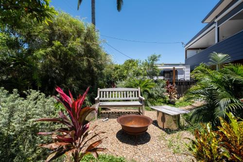 a garden with a bench and a bowl and a plant at SeaSide Serenity - beach 200m in Mudjimba