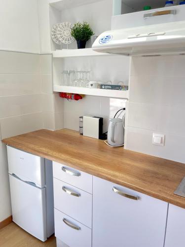 a kitchen with white cabinets and a wooden counter top at Golden Beach, Little Troll House 3 in Chrissi Akti