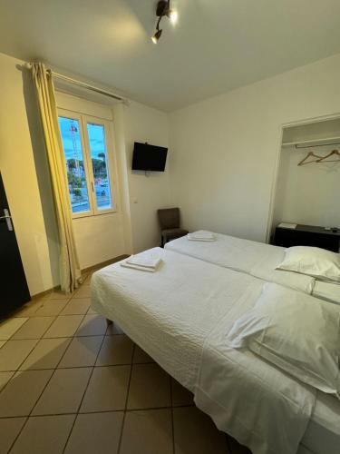 a bedroom with a large white bed and a window at Hotel La Cigale in La Croix-Valmer