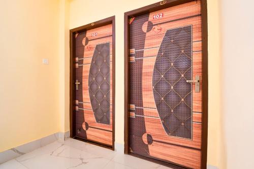 two wooden doors in a room with a wall at Hotel O Shree Jagannath Residency in Khandagiri