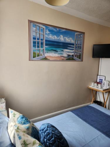 a room with a bed and a picture of the ocean at OYO Twins Palms Guest House in Great Yarmouth
