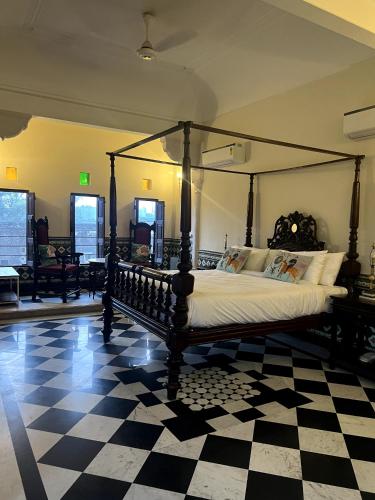 a bedroom with a canopy bed on a checkered floor at Vivaana Museum Hotel in Nawalgarh