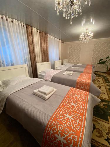a bedroom with three beds with a chandelier at RECHARGE guest house in Naryn