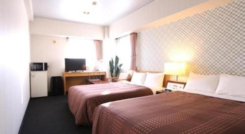 a hotel room with two beds and a television at Hotel Livemax BUDGET Chitose in Sapporo
