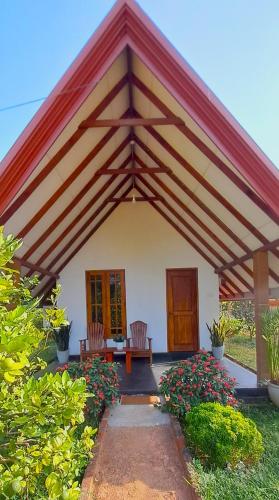 a pavilion with two chairs and a table and flowers at Sigiri Enaya Cottage in Sigiriya