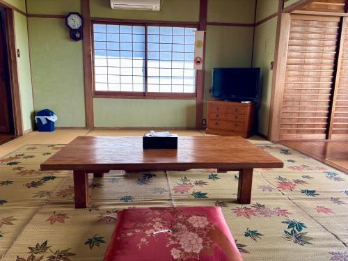 a living room with a coffee table and a tv at 和邸 和楽 Waraku in Kurume