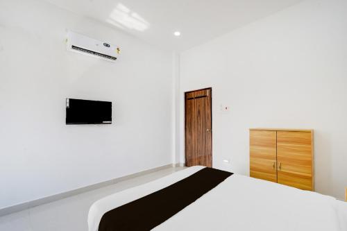 a white bedroom with a bed and a tv at Hotel O Nayati Grand in Hyderabad