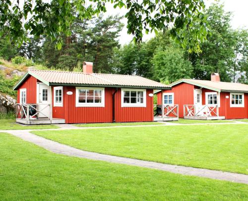 a red and white building with a grass yard at Kvibergs Stugor - Cottages in Gothenburg