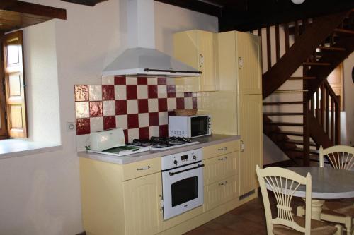 une cuisine avec une cuisinière et un micro-ondes dans l'établissement Le Manoir du Conquérant - Baie du Mont-St-Michel, à Baguer-Pican