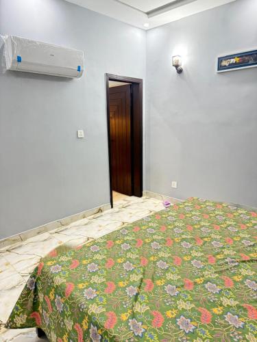 a bedroom with a bed with a flowered blanket at Malik House Bahria town Karachi, Ali block in Karachi