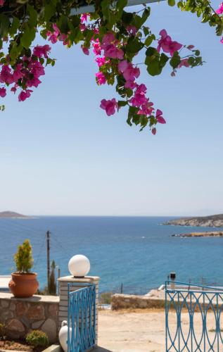 a view of the ocean from under a tree with pink flowers at Aigaio View Studios & Rooms in Azolimnos