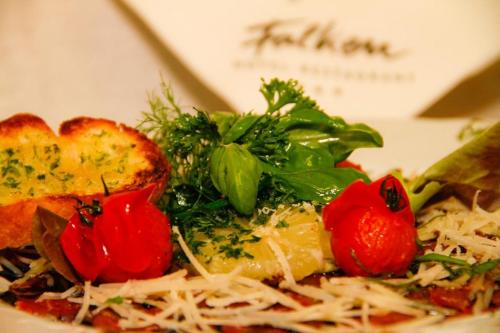 a plate of food with pasta and tomatoes and greens at Hotel Restaurant Falken in Baiersbronn