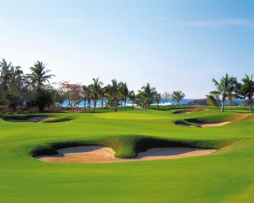 a golf course with palm trees and a hole at Four Seasons Resort Punta Mita in Punta Mita