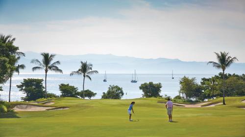 two people standing on a golf course near the ocean at Four Seasons Resort Punta Mita in Punta Mita