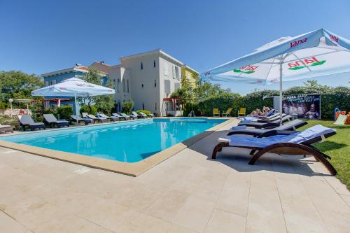 a pool with lounge chairs and umbrellas at a hotel at Hotel Manora in Nerezine