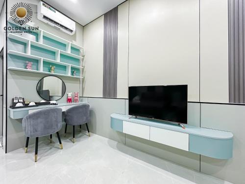 a room with a desk with a television and chairs at Golden Sun Hotel Apartments 5 in Ho Chi Minh City