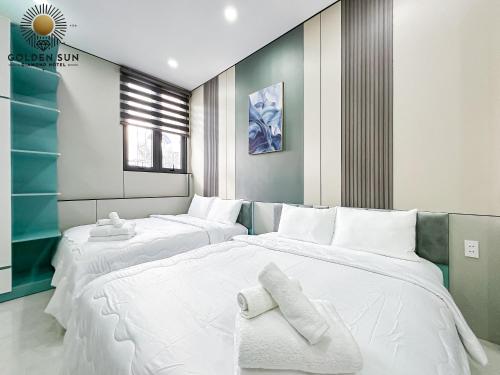 two beds in a room with white sheets and towels at Golden Sun Hotel Apartments 5 in Ho Chi Minh City