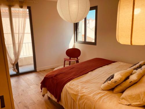 a bedroom with a bed and a chair and windows at La Maison Cavet 5 Appartements de standing au cœur du village in Sanary-sur-Mer