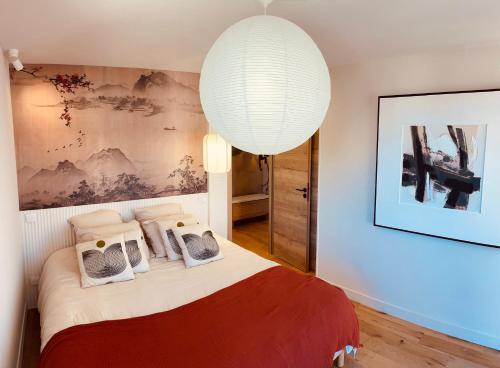 a bedroom with a large bed with a large chandelier at La Maison Cavet 5 Appartements de standing au cœur du village in Sanary-sur-Mer