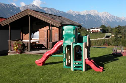 un parque infantil con un tobogán en el césped con montañas en Hotel Sonnhof, en Innsbruck