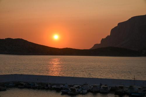 a sunset over a body of water with boats at Australia Apartments in Kalymnos