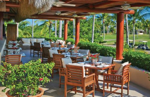 a restaurant with tables and chairs and palm trees at Four Seasons Resort Punta Mita in Punta Mita