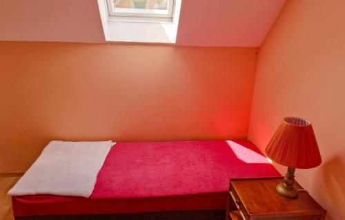 a bedroom with a pink bed with a lamp and a window at Holiday Home Rewal Olszynowa in Rewal