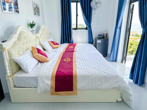 a white bed in a room with blue curtains at Sea View Hotel Phan Thiet in Bình Sum