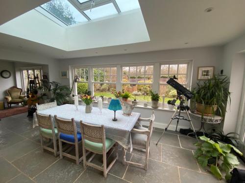 a dining room with a table and some plants at Four bedroom Rural home in the South Downs in Linchmere