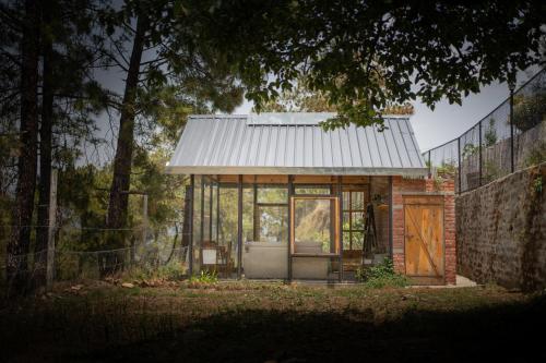 a small house with a metal roof and a door at Jaadooghar The Chitai Life in Almora