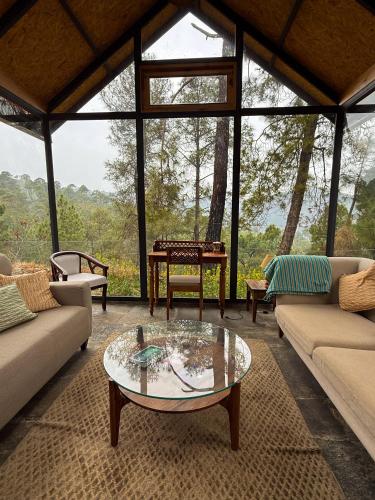 a living room with couches and a glass table at Jaadooghar The Chitai Life in Almora