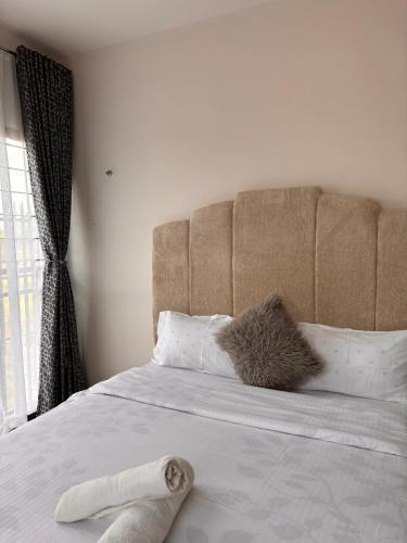 ein Bett mit braunem Kopfteil und weißen Kissen in der Unterkunft Sparkles B&Bs in Nairobi
