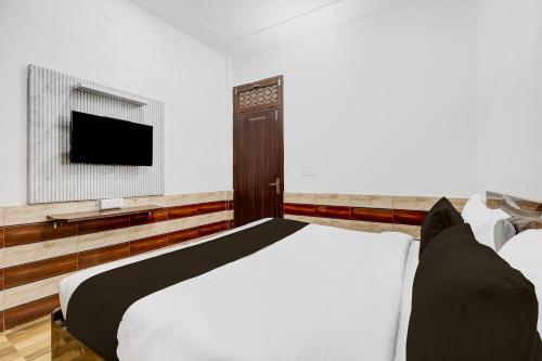 グルガオンにあるHotel O Ekant Guest Houseのベッドと薄型テレビのある寝室