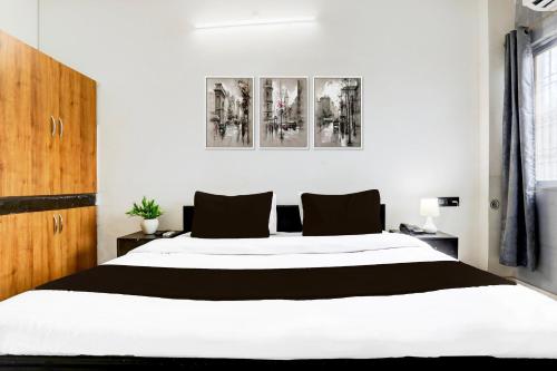 a bedroom with a large white bed with black pillows at Hotel O Shivam Grand in Gorakhpur